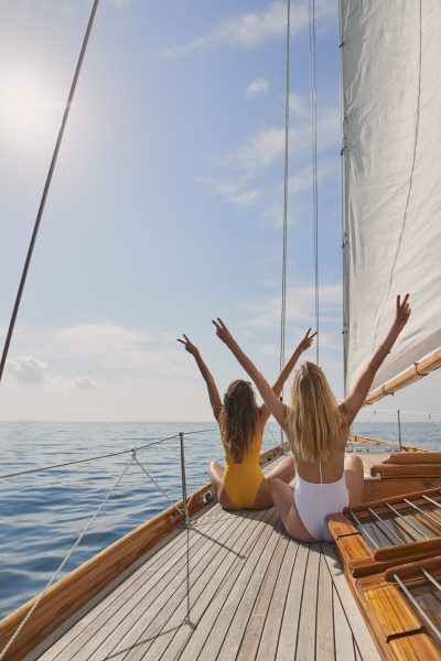 Beautiful,women,friends,celebrate,arms,raised,peace,sign,on,sailboat
