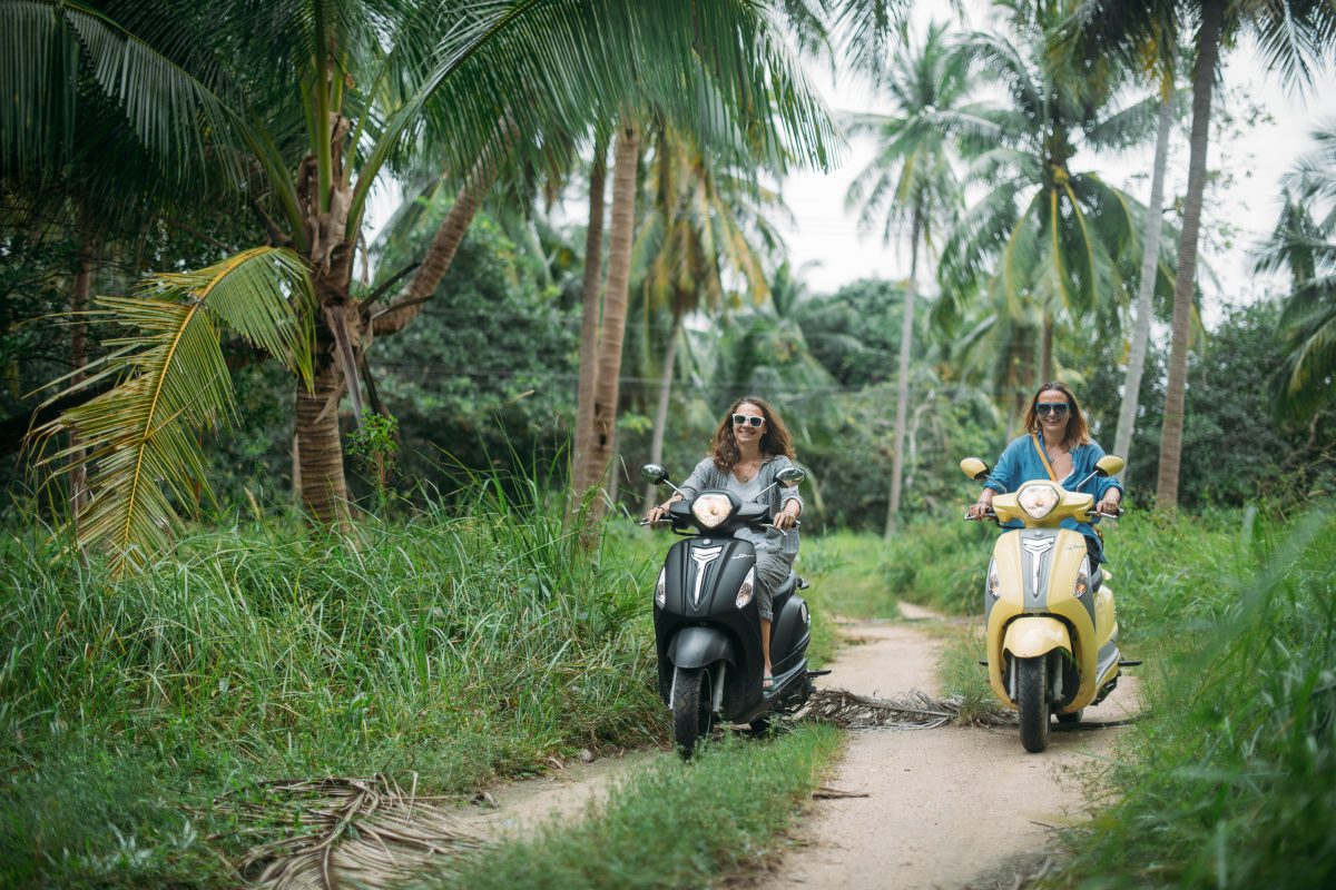 A,pair,of,beautiful,women,travel,by,scooter,through,the