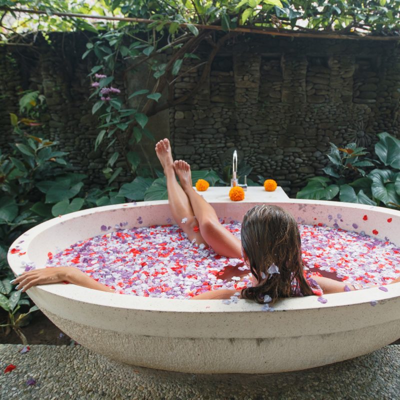 Back,view,young,woman,relaxing,in,bath,with,petals,in